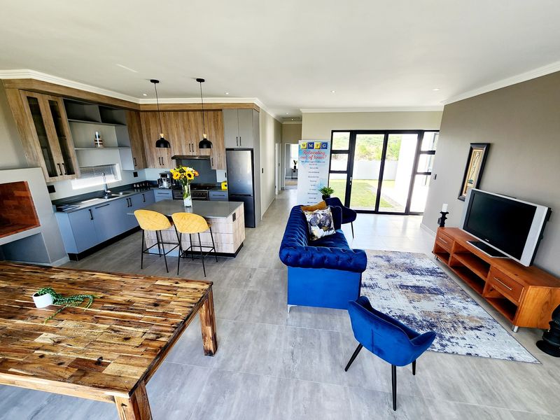 Spacious open-plan living area featuring a modern kitchen with island, tiled floors, and large sliding doors leading to the outdoor space.