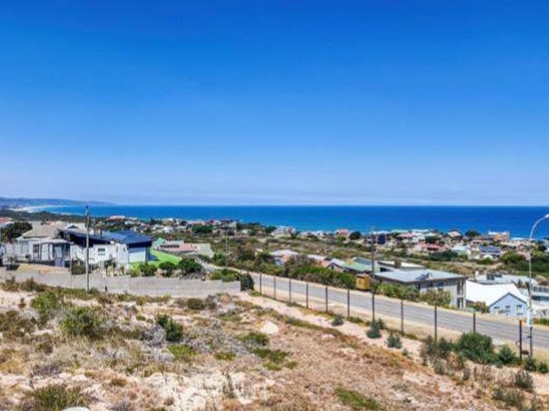 A wide-angle view of the coastal landscape, showcasing the surrounding neighborhood and expansive ocean horizon.