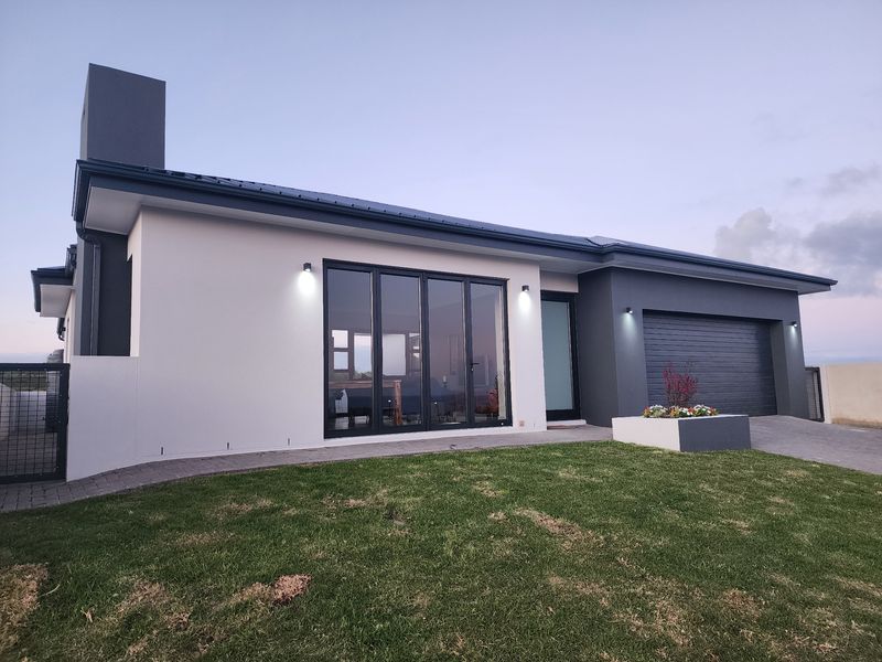 Modern single-story home exterior featuring a double garage, paved driveway, sleek bi-fold doors, and contemporary exterior lighting.