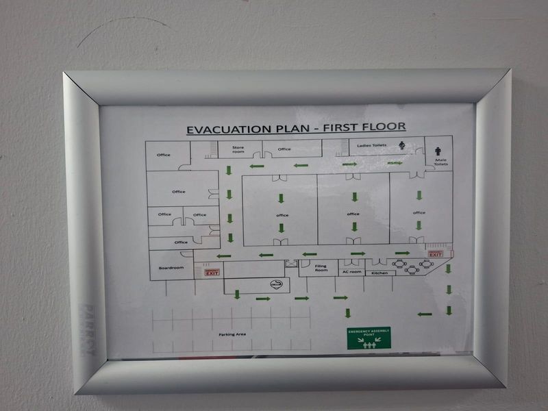A framed evacuation plan for the first floor of the commercial property, detailing office layouts, amenities, and emergency exit routes.