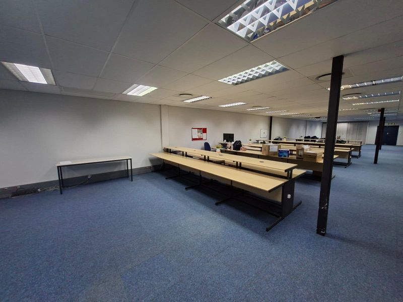 Open-plan commercial office space featuring a suspended ceiling, recessed lighting, and carpeted flooring with integrated structural support columns.