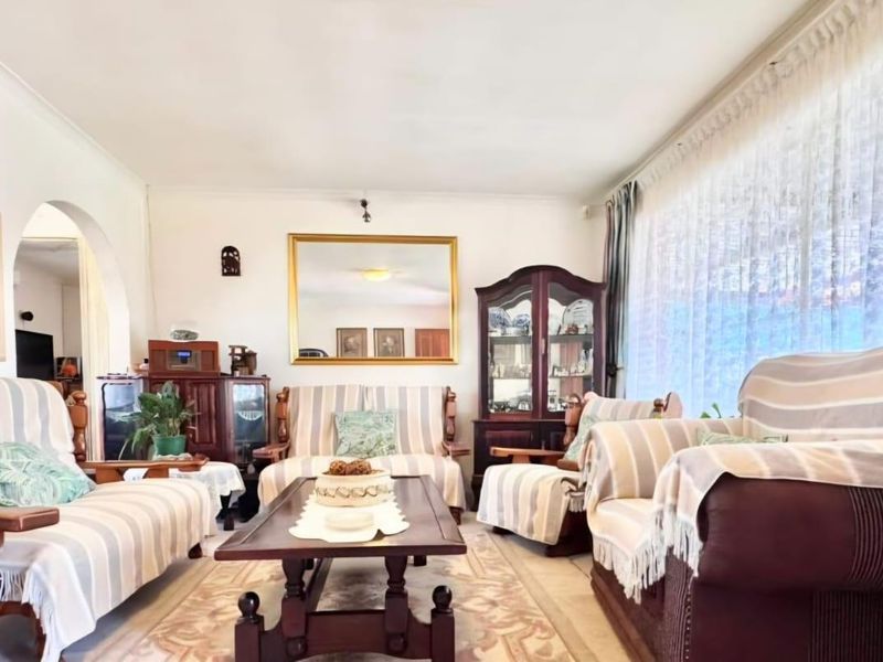 A spacious living room featuring a large window, coved ceilings, and an arched entryway leading to adjacent living areas.