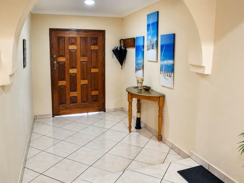 A welcoming entrance hall featuring tiled flooring, a solid wood front door, and decorative arched architectural details.