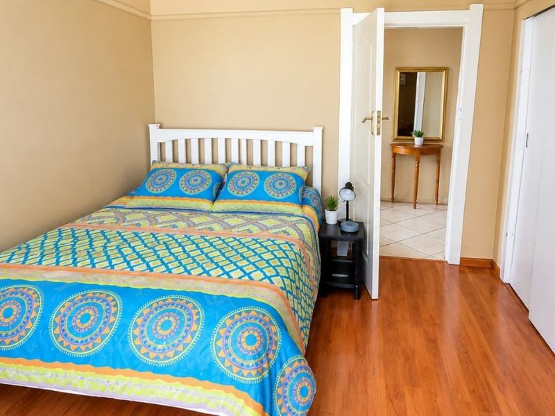 A bedroom featuring laminate flooring, a built-in wardrobe, and neutral wall tones, offering a functional and well-maintained living space.