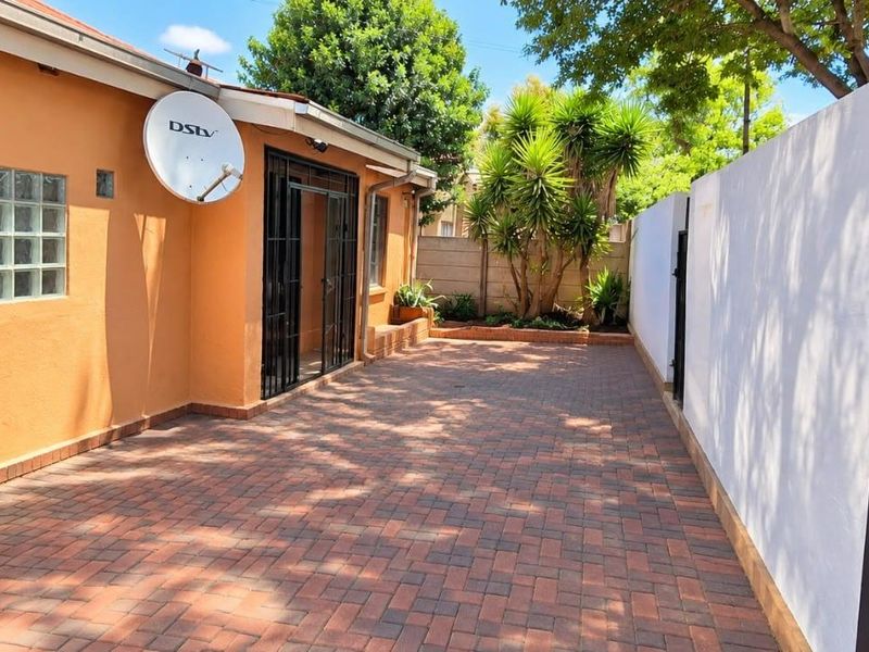 A well-maintained paved rear courtyard area featuring a boundary wall, security gate, and exterior access to the main dwelling.