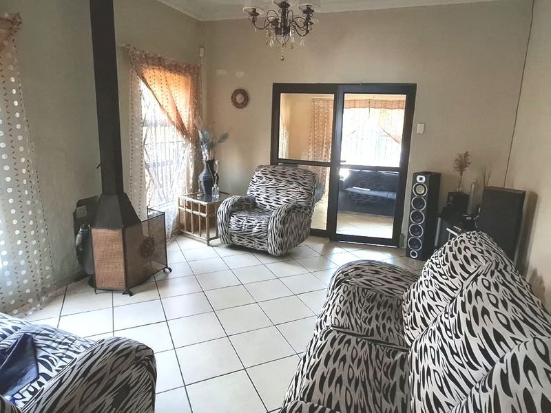 A living room featuring tiled flooring, a freestanding fireplace, and a sliding glass door leading to an adjacent space.