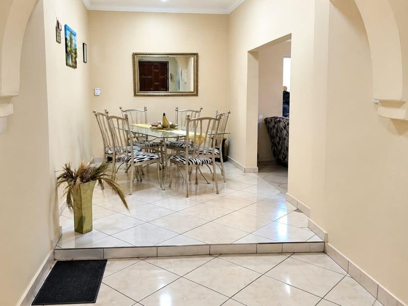 A dining area featuring tiled flooring, a raised floor section, and architectural archways connecting to adjacent living spaces.