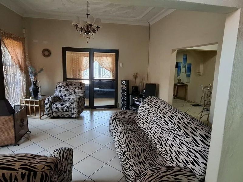 A living room featuring tiled flooring, a freestanding fireplace, and decorative ceiling molding, with a sliding door providing access to the exterior.