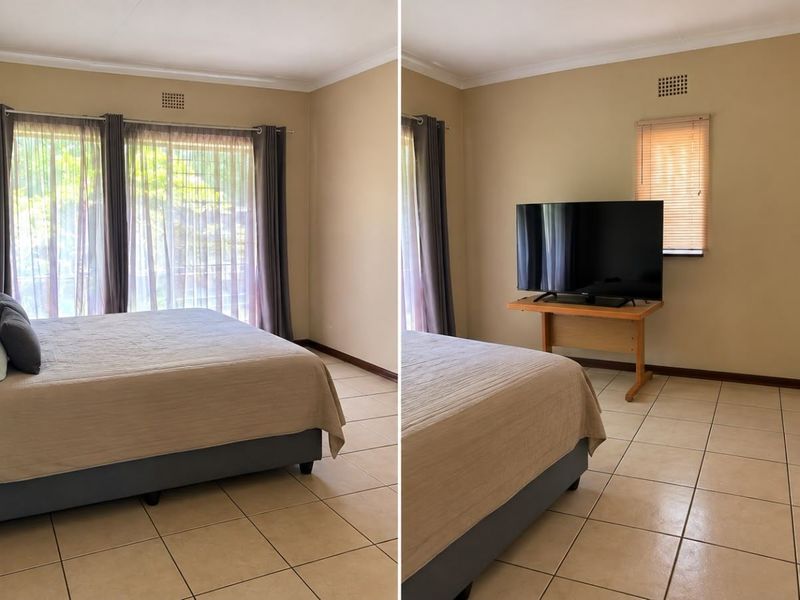 Spacious bedroom featuring neutral tiled flooring, large sliding glass doors for natural light, and a built-in air vent.