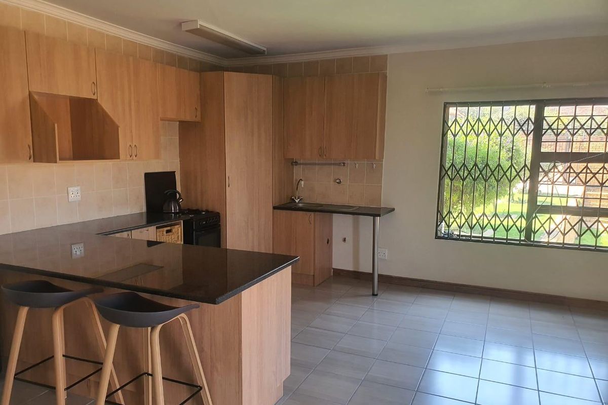 Functional kitchen featuring laminate cabinetry, granite countertops, tiled flooring, and a window with security bars, offering a practical layout for daily use.