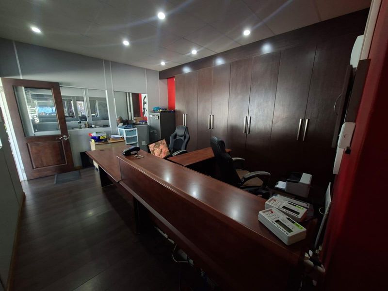 A professional office space featuring extensive built-in dark wood cabinetry, a large reception desk, and recessed ceiling lighting.