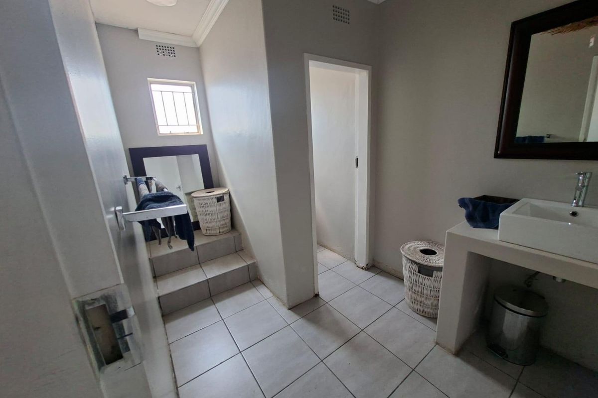 A functional bathroom featuring tiled flooring, a built-in vanity with a basin, and a small window with security bars.