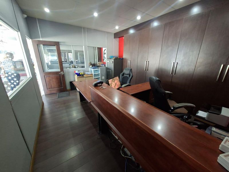 A professional office space featuring extensive built-in dark wood cabinetry, a reception desk, and modern laminate flooring with recessed lighting.