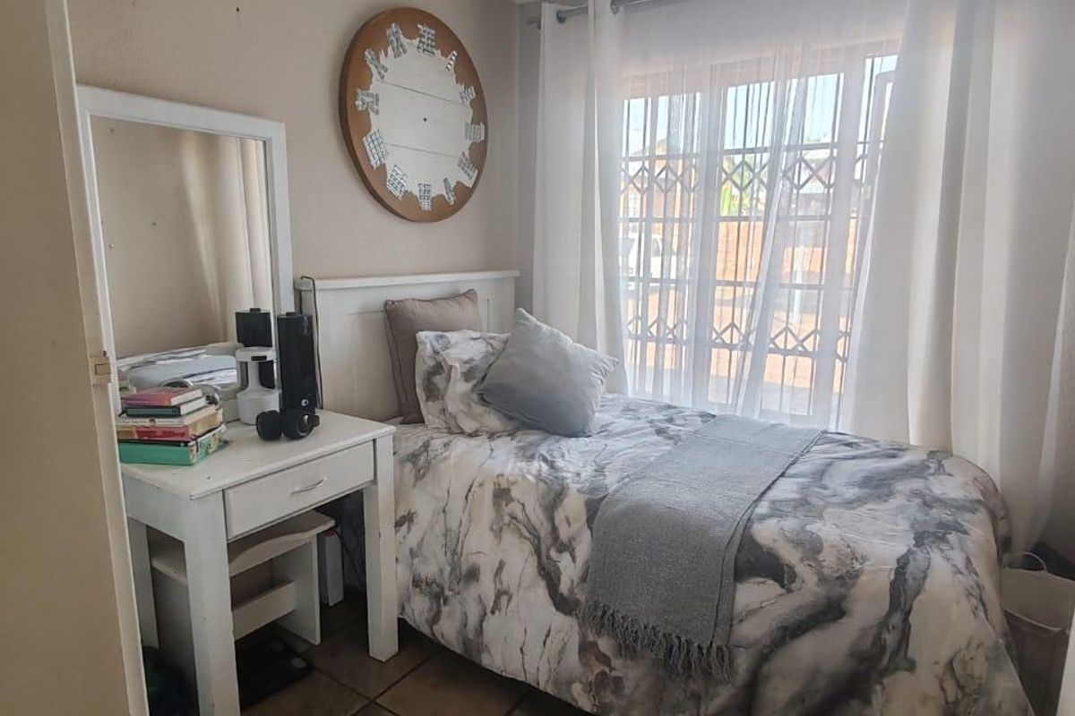 A compact bedroom featuring tiled flooring, a security gate on the window, and a ceiling-mounted spotlight fixture.