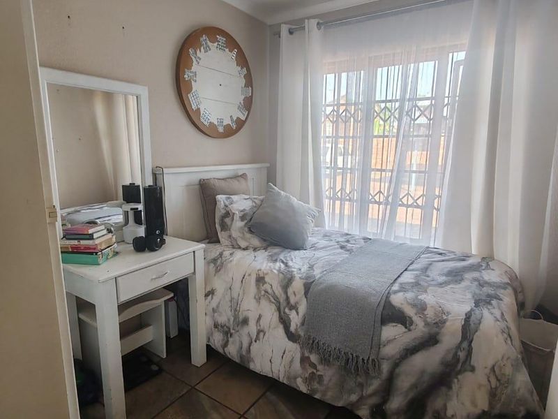 A compact bedroom featuring tiled flooring, a security gate on the window, and a ceiling-mounted spotlight fixture.