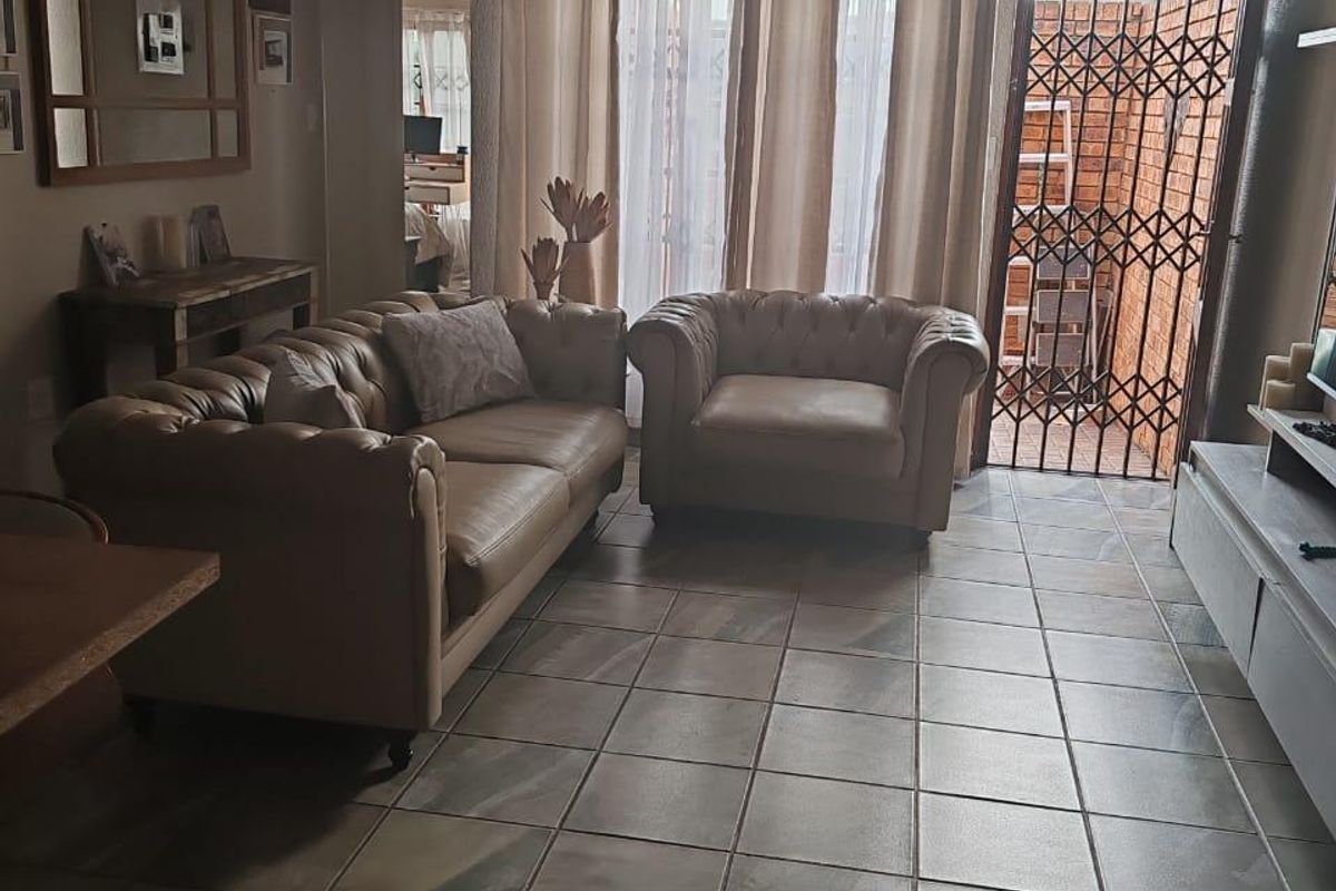A living room featuring tiled flooring, a ceiling light fixture, and a sliding glass door leading to a secure outdoor area.