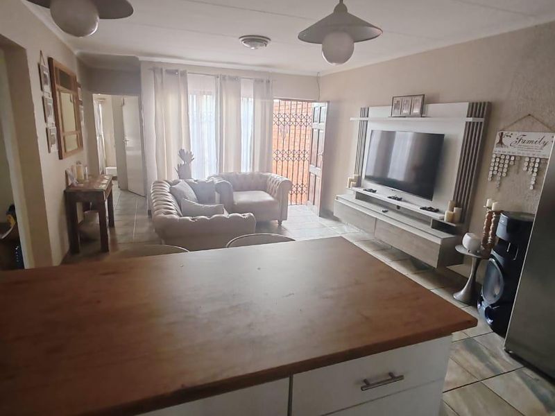 Open-plan living area featuring a kitchen with wooden countertops, tiled flooring, and a built-in media unit, leading to an outdoor access point.