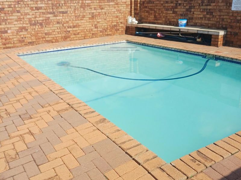 A private swimming pool area featuring brick paving and a high brick boundary wall, providing a secure and enclosed outdoor space.