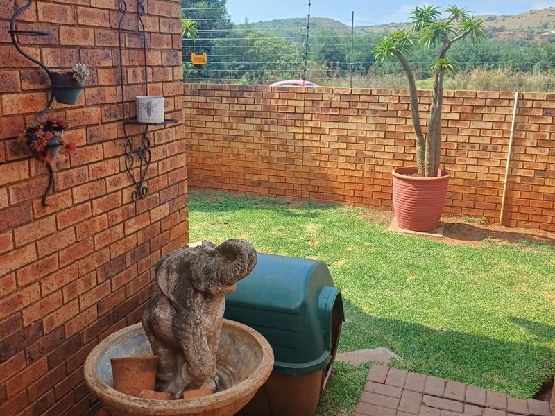 A private rear garden featuring a face brick wall, paved walkway, and secure perimeter walling with electric fencing.