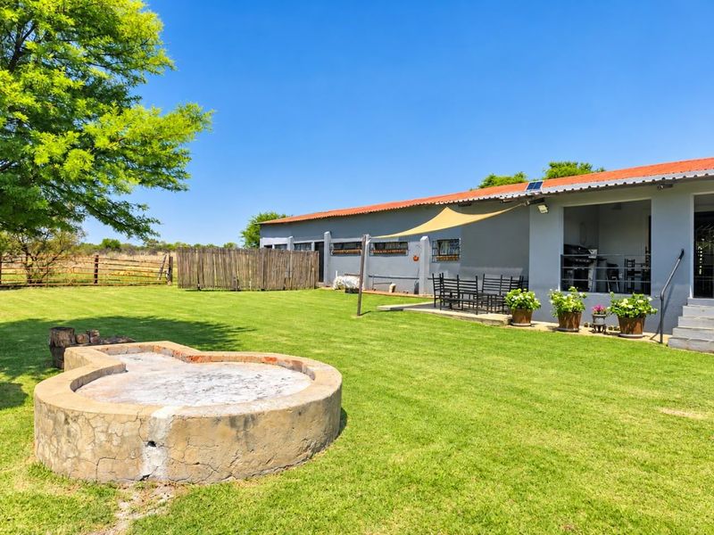 Spacious rear garden featuring a built-in fire pit, a covered patio area with a shade sail, and well-maintained lawn space.
