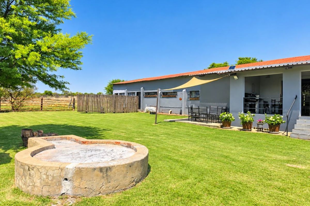 Spacious rear garden featuring a built-in fire pit, a covered patio area with a shade sail, and well-maintained lawn space.