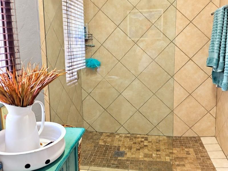 A bathroom featuring a walk-in shower with a glass screen, tiled walls, and a mosaic tiled shower floor.