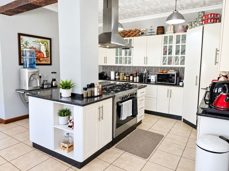 A well-maintained kitchen featuring white shaker cabinetry, granite countertops, a gas cooktop with stainless steel extractor, and decorative tiled backsplash.