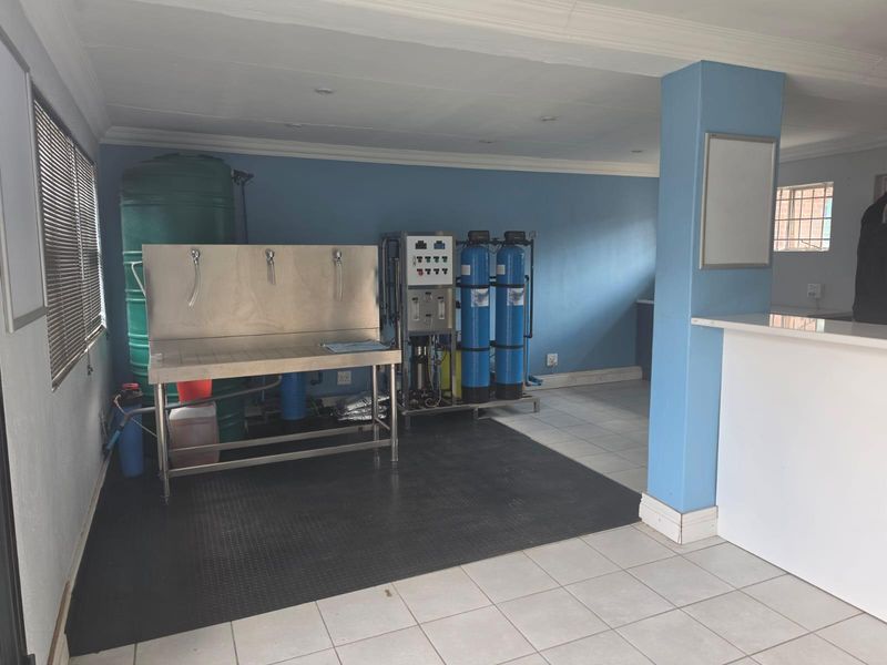 A functional utility space equipped with a professional water filtration system, stainless steel prep station, and large water storage tank.