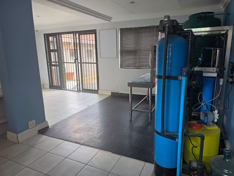 A functional utility space featuring a built-in water filtration system, durable tiled and rubber flooring, and secure access to the exterior.