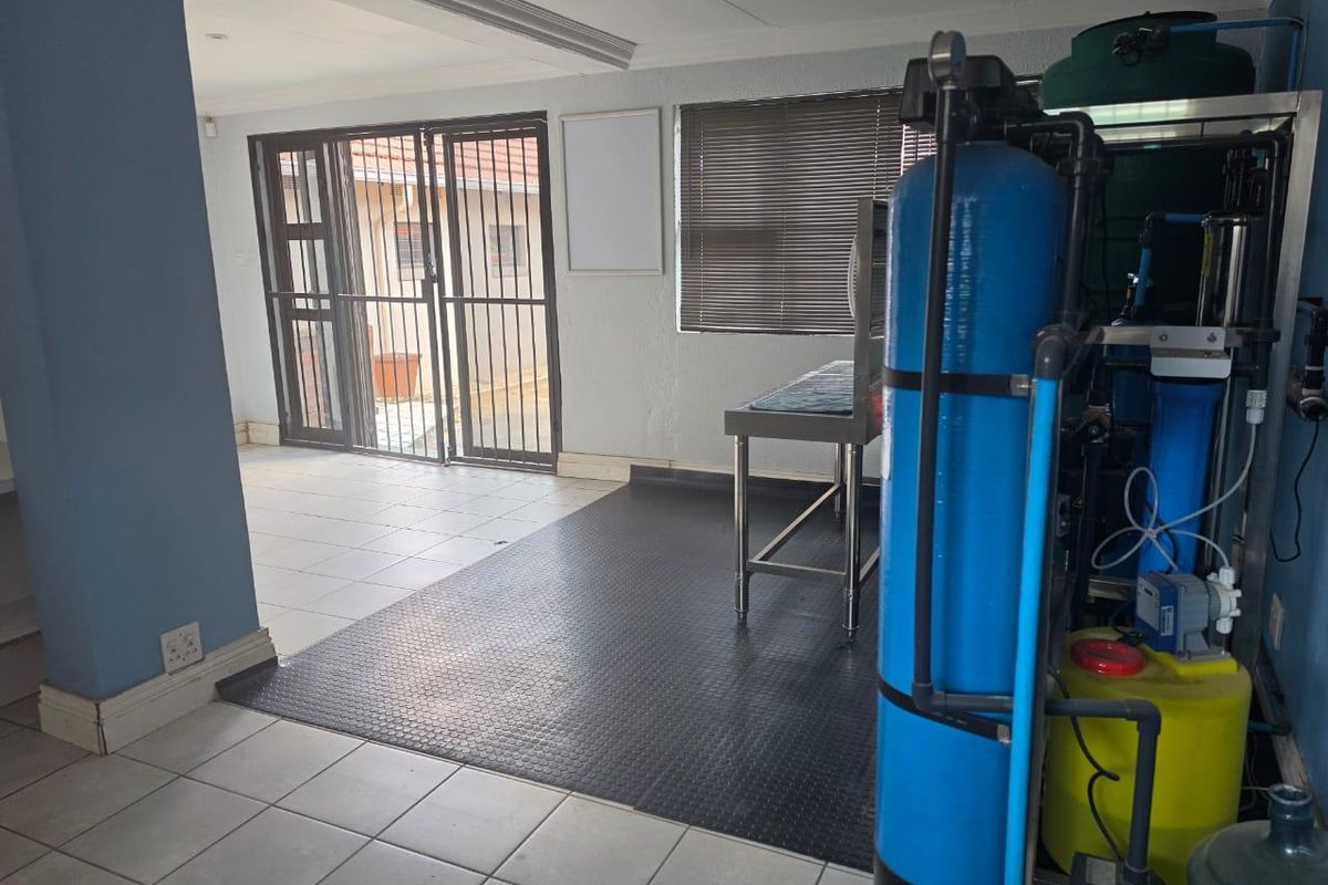 A functional utility space featuring a built-in water filtration system, durable tiled and rubber flooring, and secure access to the exterior.