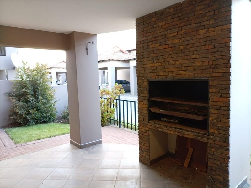 Covered patio area featuring a built-in stone-clad braai, tiled flooring, and direct access to the garden.