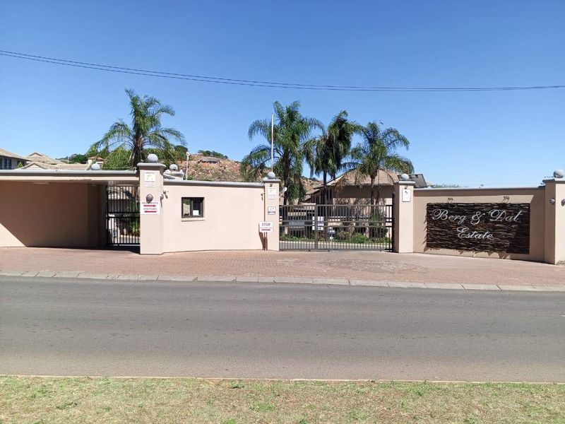 Front entrance view of Berg & Dat Estate featuring a secure gated access point, perimeter walling, and paved driveway.
