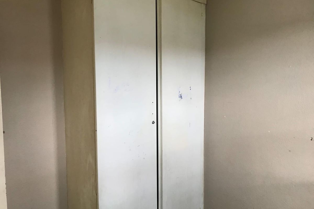 A bedroom featuring a built-in wardrobe with visible wear and surface marks on the doors.