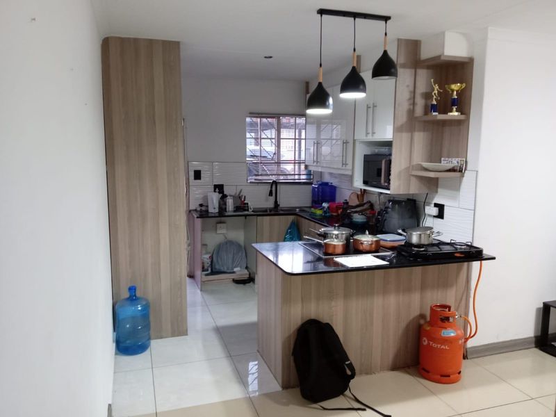 A functional kitchen featuring wood-look cabinetry, granite countertops, a built-in hob, and modern pendant lighting, offering a practical layout for daily meal preparation.