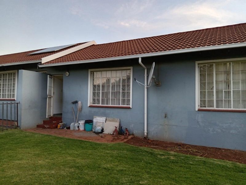 Rear exterior view of the townhouse featuring a tiled roof, solar water heating panel, and security window bars.