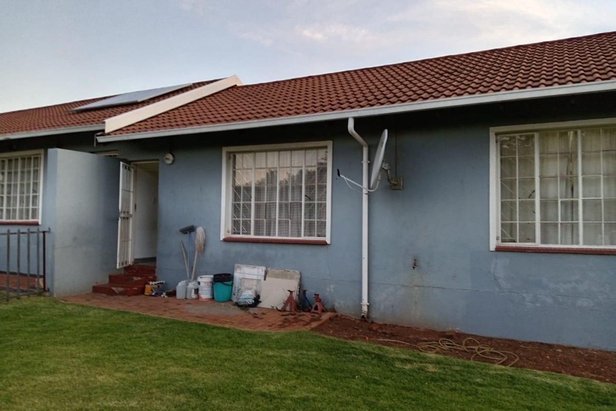 Rear exterior view of the townhouse featuring a tiled roof, solar water heating panel, and security window bars.