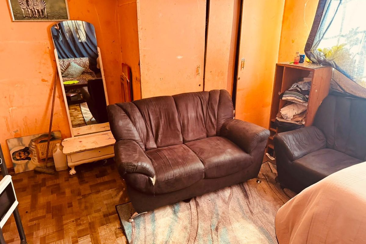 A living room featuring parquet flooring and built-in cupboards, currently requiring cosmetic updates and wall refinishing to improve the overall aesthetic.