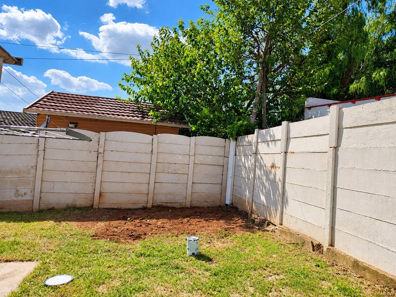 A rear garden area featuring a precast concrete boundary wall and a patch of exposed soil, offering potential for landscaping and outdoor improvement.