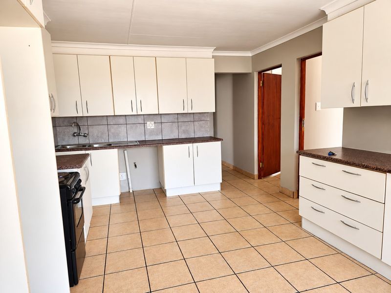 A functional kitchen featuring white built-in cabinetry, laminate countertops, tiled backsplash, and ceramic floor tiles, offering a clean and practical workspace.