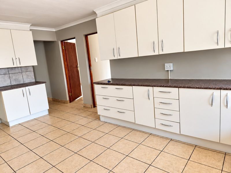 A clean, functional kitchen featuring white cabinetry, laminate countertops, and neutral ceramic floor tiles, offering a blank canvas for modern updates.