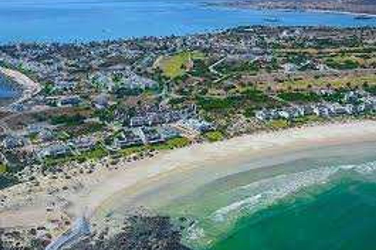 An aerial view of the coastal residential area and beach, showcasing the property's proximity to the ocean and surrounding landscape.