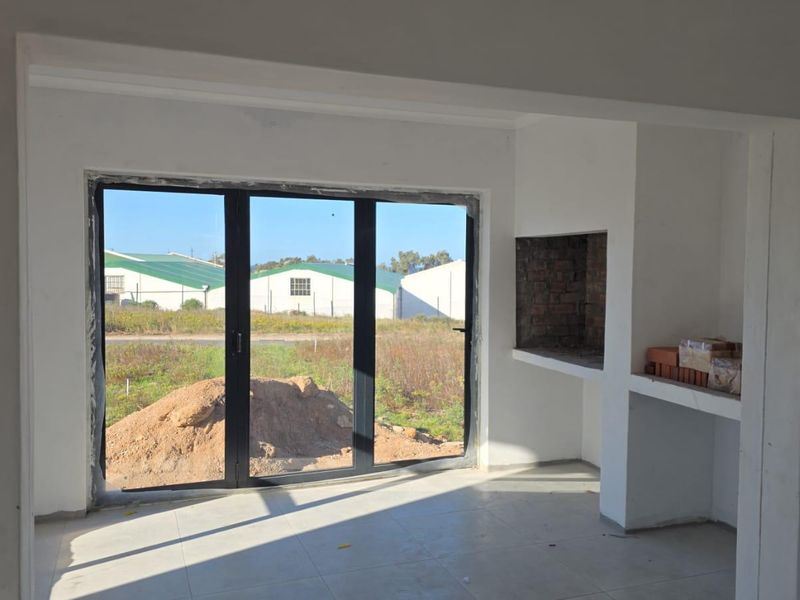 An empty, unfinished living area featuring tiled floors, a built-in fireplace, and large aluminium stacker doors leading to the exterior.