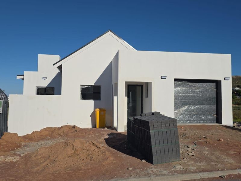 Front elevation of a modern house under construction, featuring a single garage, clean white facade, and unfinished landscaping.