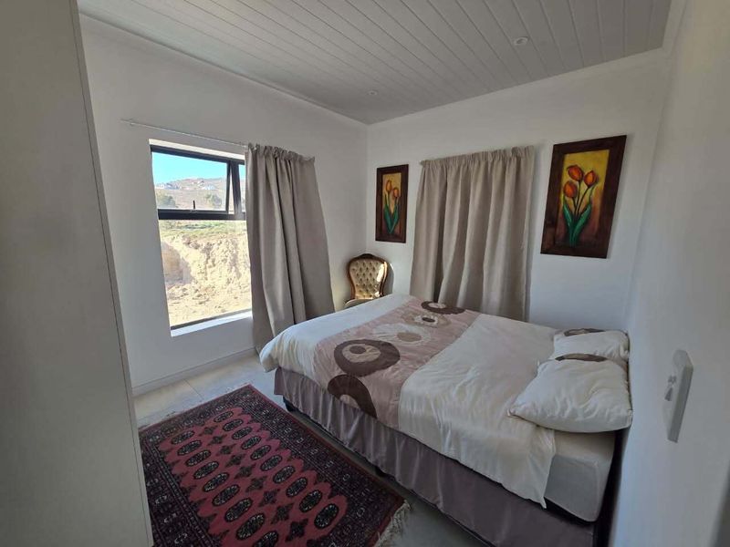 A bedroom featuring a tongue and groove ceiling and an aluminium window frame, offering a functional space with natural light.