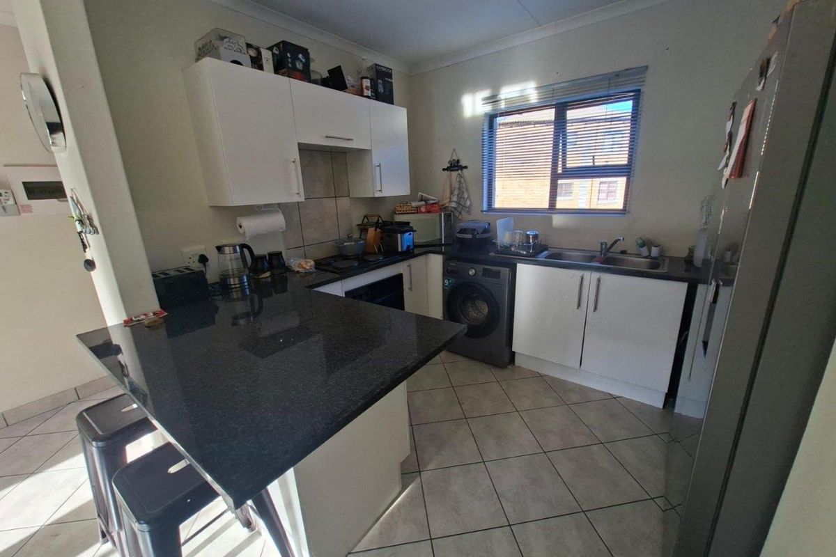 Compact kitchen featuring dark granite countertops, white cabinetry, tiled flooring, and integrated space for a washing machine.