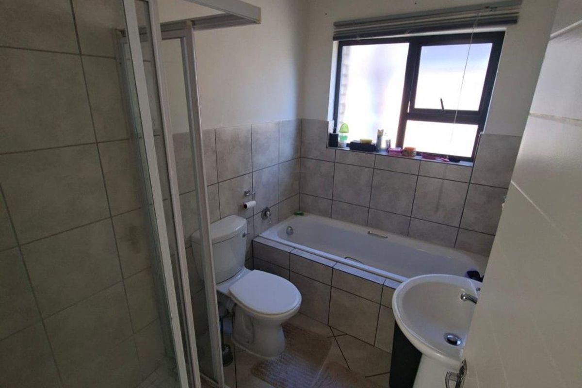 A functional bathroom featuring a separate shower enclosure, a bathtub, a pedestal sink, and tiled flooring and walls.