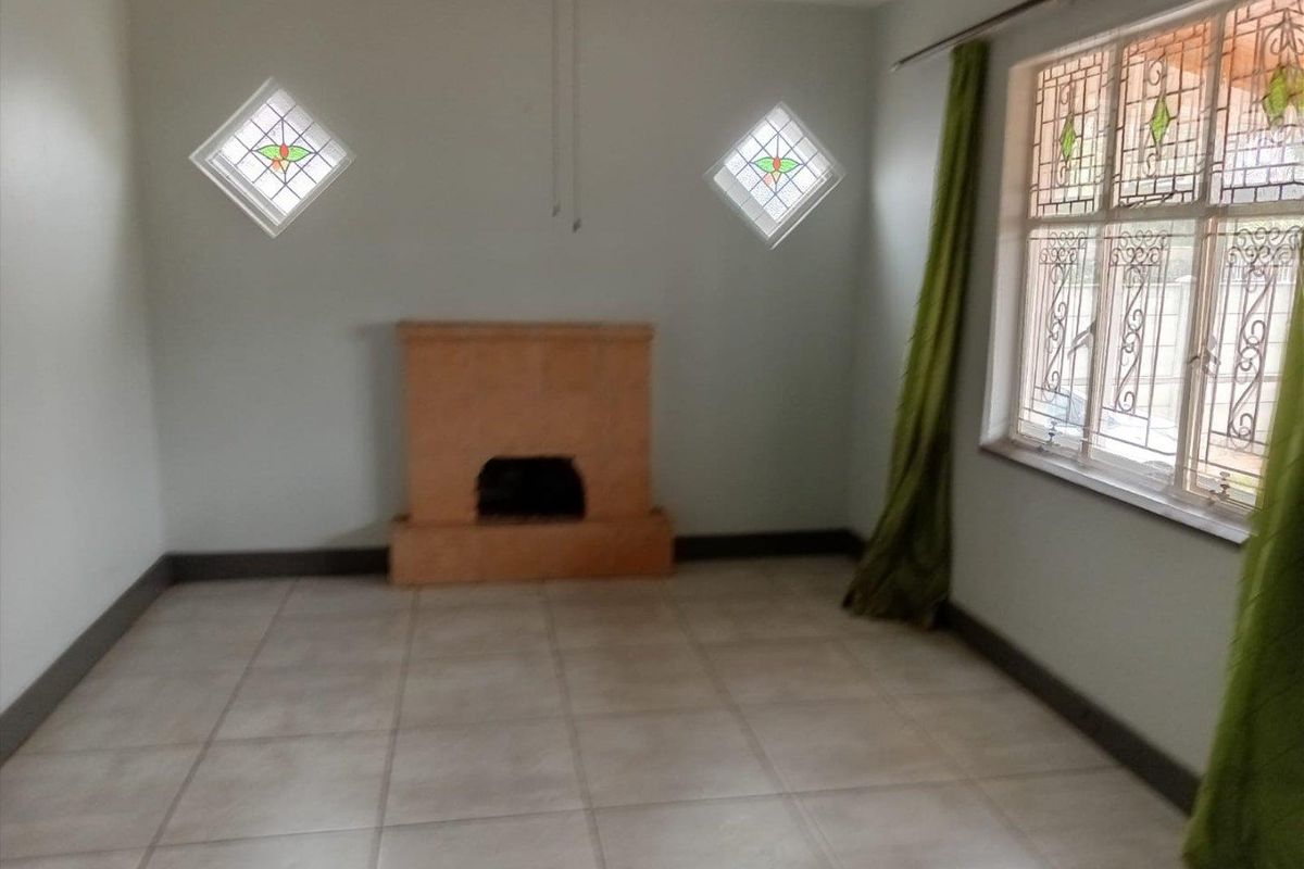 A living room featuring tiled flooring, a central fireplace, and decorative diamond-shaped stained glass windows.