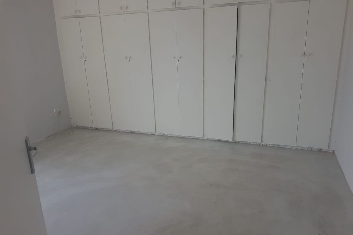 A bedroom featuring extensive built-in floor-to-ceiling cabinetry and a smooth concrete-style floor finish.