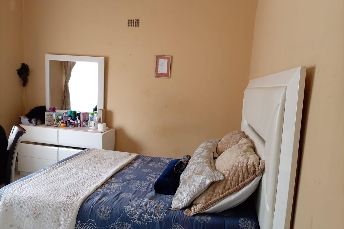 A bedroom featuring plain painted walls and a built-in ventilation vent.