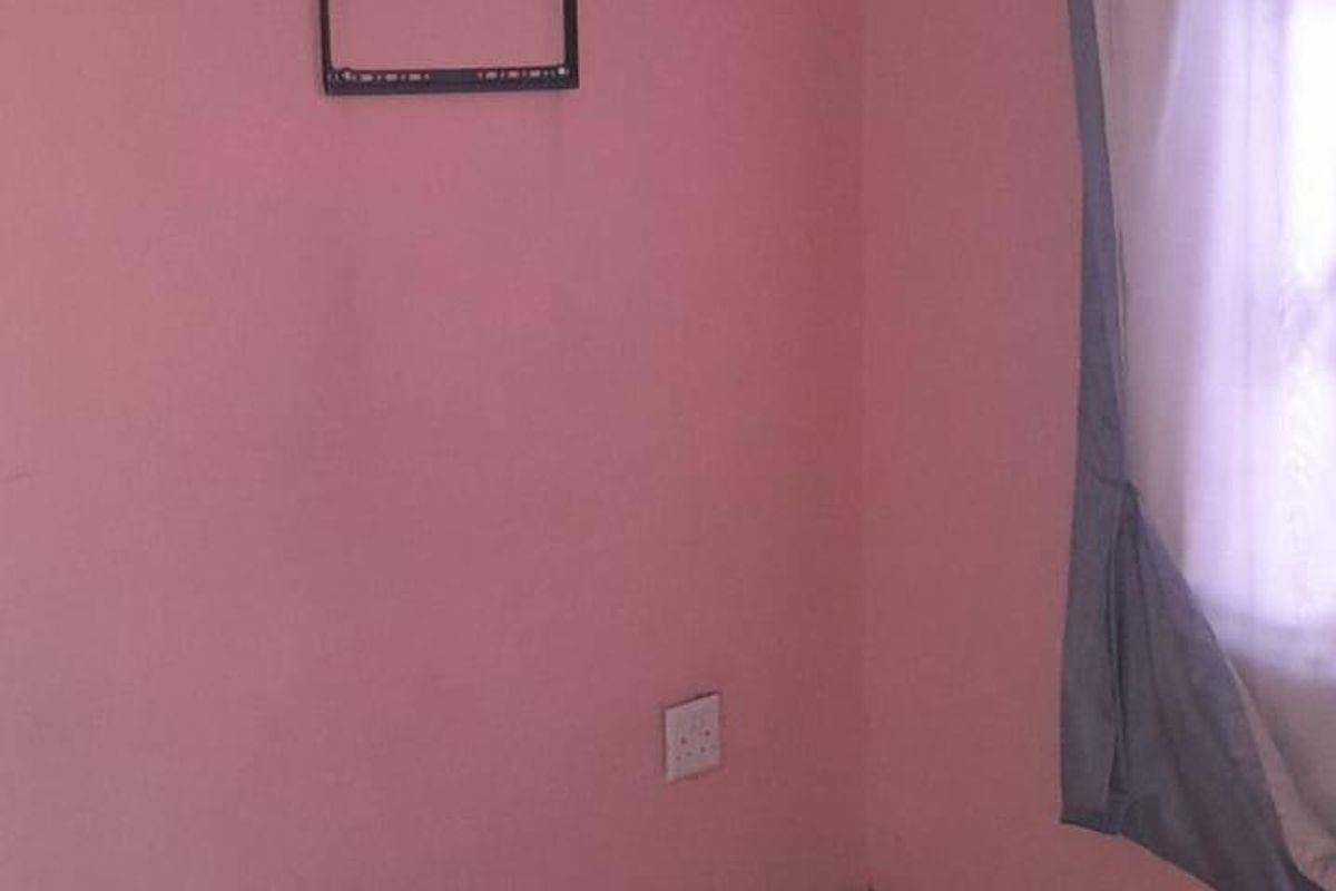 A vacant bedroom featuring pink painted walls, tiled flooring, and a wall-mounted TV bracket.